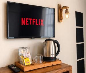 a television on a wall with a kettle on a table at Blue Sea Hotel in Tuzla