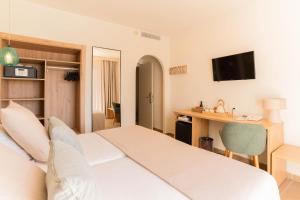 a hotel room with a white bed and a desk at Hotel Cala Dor - Adults Only in Cala d´Or