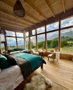a bedroom with a bed in a room with large windows at Alto Castillo Lodge in Villa Cerro Castillo