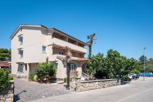 a large white house with a palm tree in front of it at Sto Rija in Krk