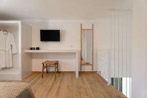 a white room with a chair and a tv on a wall at Serenity Villas in Ios Chora
