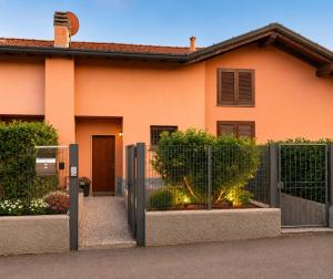 a orange house with a fence and a gate at Lilly House Perfect stopover near Lake Como Switzerland and Milan in Fino Mornasco