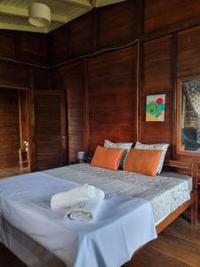 a bedroom with a large bed with wooden walls at Pousada Vila Paraíso in Santa Cruz