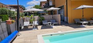 a swimming pool with chairs and umbrellas next to a building at Alessio Camere in Bardolino