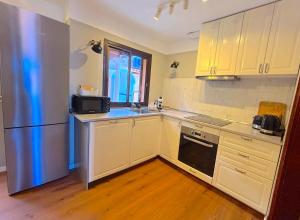 a kitchen with white cabinets and a stainless steel refrigerator at Villa Casa Papaya - All Year Heated Pool in La Orotava