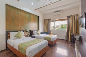 a hotel room with two beds and a television at R D Hotels HSR in Bangalore