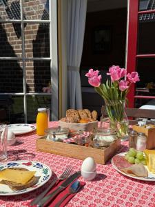a table with pink flowers and food on a table at BnB 't Ambacht - Boutique Hotel in Hendrik-Ido-Ambacht