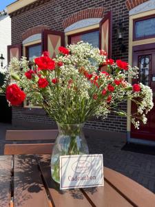 a vase filled with red and white flowers on a table at BnB 't Ambacht - Boutique Hotel in Hendrik-Ido-Ambacht