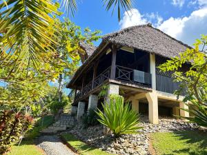 ein Haus mit Reetdach und einem Garten in der Unterkunft Villa TiPunch in Nosy Be