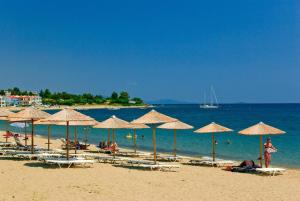 a beach with umbrellas and people on the water at Summer Dream Escape Apartment in Gerakini