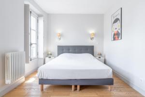 a white bedroom with a bed and two windows at Apparts de l'Oncle Louis in Versailles