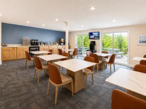 eine Cafeteria mit Tischen und Stühlen und einer Küche in der Unterkunft Cod Cove Inn, BW Signature Collection-Boothbay Harbor Area in Edgecomb