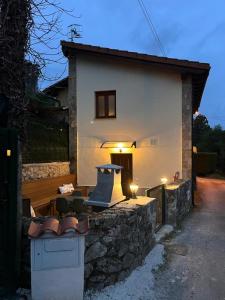 a house with a stone wall and a table and chairs at Atardecer en Gulpiyuri By Silastur in Naves