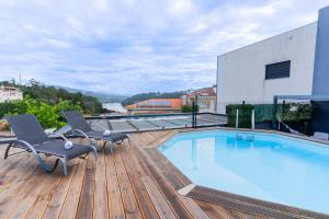 a swimming pool on a wooden deck with two chairs at Casa entre Rios in Alpendurada