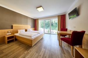 a bedroom with a bed and a desk and a window at Leni-Marie Saalbach in Saalbach-Hinterglemm +39 photos