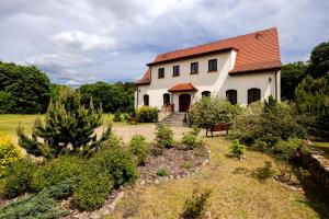 a white house with a red roof and a garden at Gospodarstwo nad jeziorem in Załom