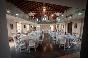 a banquet hall with white tables and white chairs at Montalbera Wine Suites in Montemagno