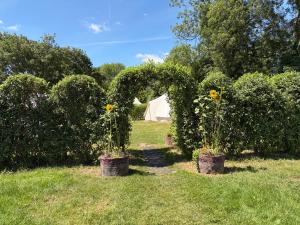 an arch with flowers in pots in a field at Camping at the Barge in Alton Barnes