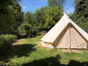 a tan tent in a yard with trees at Camping at the Barge in Alton Barnes