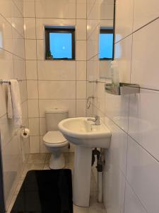a white bathroom with a toilet and a sink at Ella Guest House in Pretoria