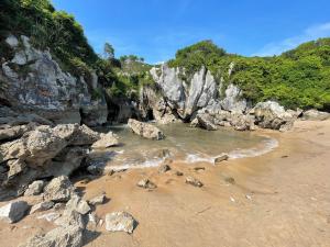 a beach with rocks and water on a beach at Atardecer en Gulpiyuri By Silastur in Naves