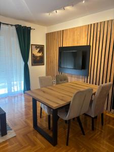 a dining room with a wooden table and a television at Vanila Ub in Ub +1 photo