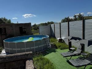 a hot tub in a yard with chairs and an umbrella at Гостевой Дом на природе in Vanadzor