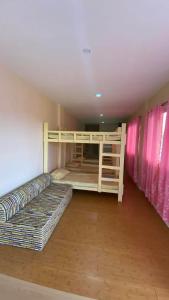 two bunk beds in a room with pink curtains at Buku Island House in san juan la union