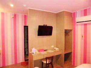 Habitación con escritorio y TV en la pared. en 欣悅商務旅店 en Toufen