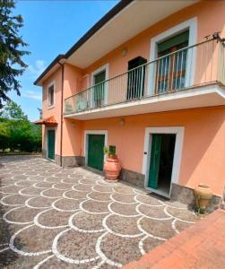 a pink house with a balcony and a patio at B&B ombra dei pini in San Leucio del Sannio
