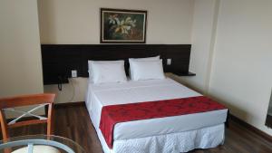a bedroom with a bed with a red blanket at Center Patos Hotel in Patos de Minas