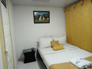 a small room with a bed with a yellow pillow at Casa hotel Comunicar Nini in Bogotá
