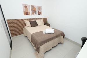 a bedroom with a bed with two towels on it at Pousada House Garden in Goiânia