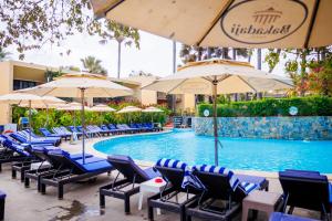 a swimming pool with blue chairs and umbrellas at Bakadaji Hotel in Serekunda