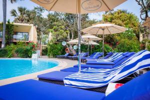 a group of blue chairs and umbrellas next to a swimming pool at Bakadaji Hotel in Serekunda