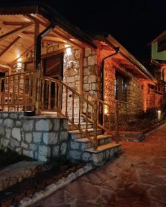 a stone house with a wooden staircase in front at Çameli doğa hotel in Belevi