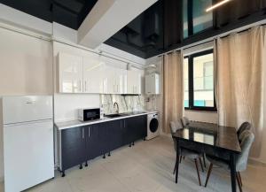 a kitchen with a table and a white refrigerator at Apartament Poseidon in Mamaia Sat/Năvodari