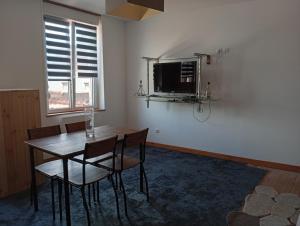 a dining room with a table and chairs and a television at L'immeuble de Didier et Fabien in Guînes