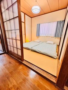 a small room with a bed and a window at 古民家一棟貸切 民宿 潤 松山市駅徒歩5分 銀天街徒歩2分 無料駐車場1台付き in Matsuyama