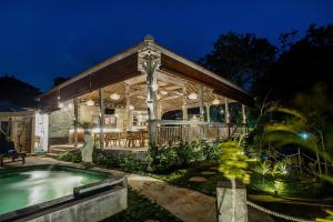 a house with a swimming pool in the yard at The Old Island Huts in Nusa Lembongan