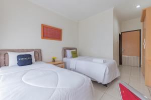 a hotel room with two beds and a red chair at Urbanview Hotel Tridaya Cisarua Puncak in Kopo 2 +31 photos