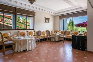 a dining room with tables and chairs and windows at Dar Zayane in Khenifra