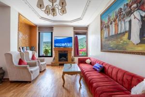 a living room with a red couch and a fireplace at Dar Zayane in Khenifra