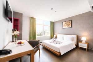 a bedroom with a bed and a table and a desk at G8 Center Hotel Saigon in Ho Chi Minh City