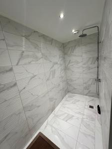 a bathroom with a shower with white marble tiles at Nōema Residences II in Nafpaktos +24 photos