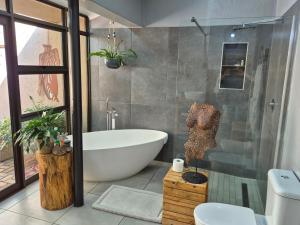 a bathroom with a bath tub and a toilet at Bendor Garden Flat in Polokwane +11 photos