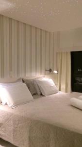 um quarto com uma cama grande e lençóis brancos em Lindo Apto em Ondina com Vista em Salvador