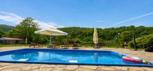 a swimming pool with an umbrella and a table and chairs at Комплекс Сборяна in Gramatikovo