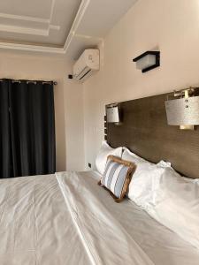 a bedroom with a large white bed with a wooden headboard at AMINA luxury SUITE in Lomé