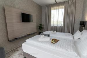 two white beds in a hotel room with a television at Szauter Aparthomes A in Győr